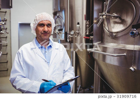 Manufacturer with writing pad standing at brewery 31909716