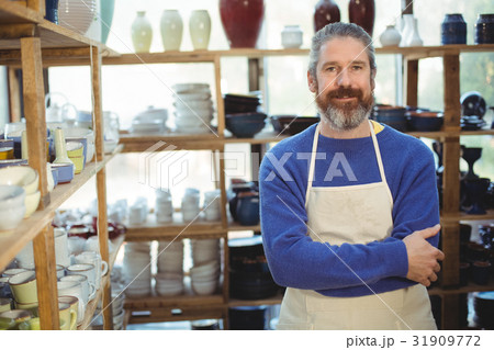 Happy male potter standing in pottery workshop Happy male potter standing in pottery workshop 31909772