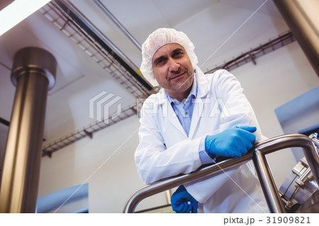 Smiling manufacturer leaning on pipe at brewery Smiling manufacturer leaning on pipe at brewery 31909821