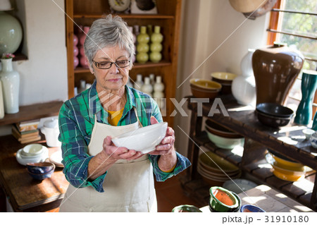 Female potter checking bowl Female potter checking bowl 31910180