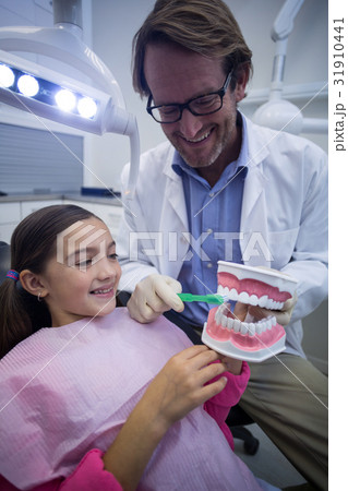 Dentist showing young patient how to brush teeth Dentist showing young patient how to brush teeth 31910441