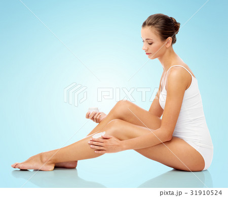 woman applying moisturizing cream to her leg woman applying moisturizing cream to her leg 31910524