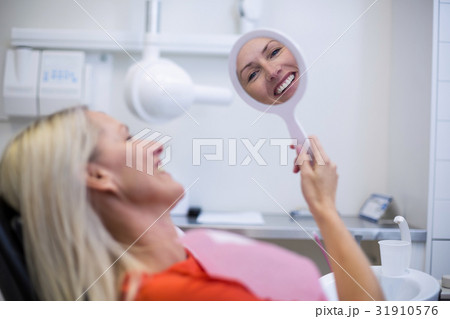 Patient checking her teeth in mirror 31910576