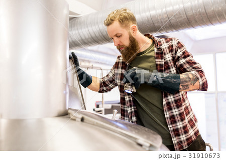 man working at craft brewery or beer plant man working at craft brewery or beer plant 31910673