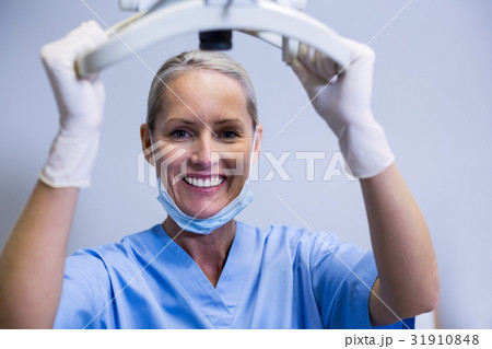 Smiling dental assistant adjusting light in clinic 31910848