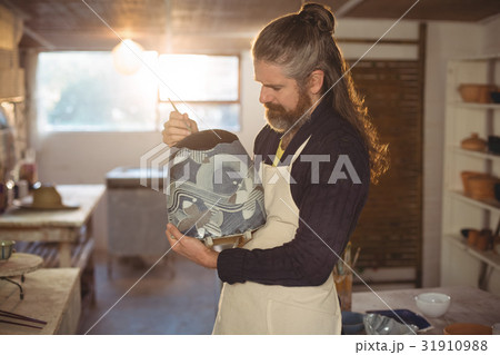 Attentive male potter painting on pot 31910988