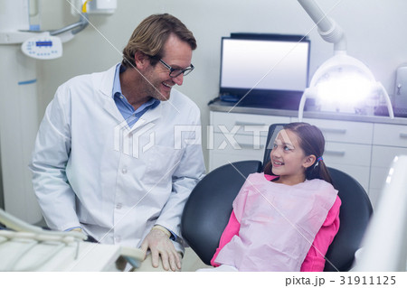 Smiling dentist talking to young patient Smiling dentist talking to young patient 31911125