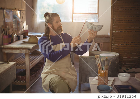 Attentive male potter painting on bowl 31911254
