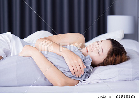 Woman sleeping with bolster pillow on bed in bedroom Woman sleeping with bolster pillow on bed in bedroom 31918138