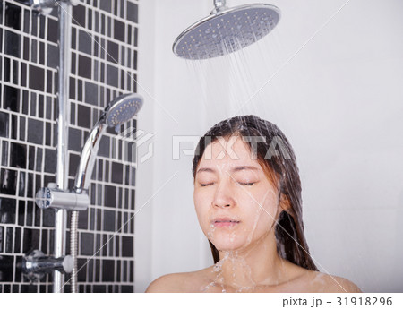 Woman is washing her hair and face by rain shower 31918296