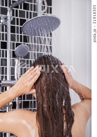 woman is washing her hair and face by rain shower, rear view woman is washing her hair and face by rain shower, rear view 31918305