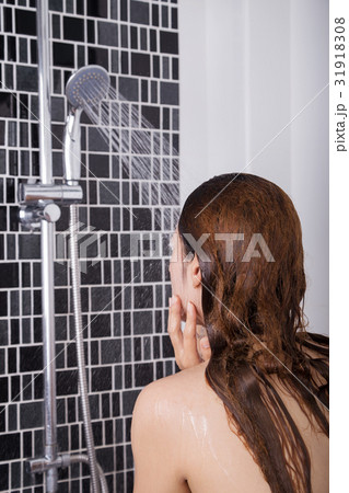 Woman is washing her face by shower, rear view Woman is washing her face by shower, rear view 31918308