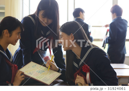色紙に寄せ書きをする卒業生 31924061