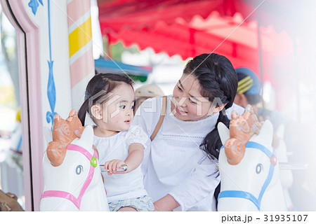 親子 家族旅行 テーマパーク 遊園地 メリーゴーランドの写真素材