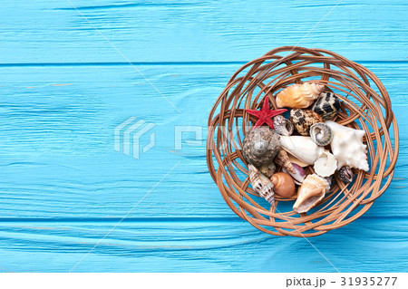 Seashells in basket, blue background. 31935277