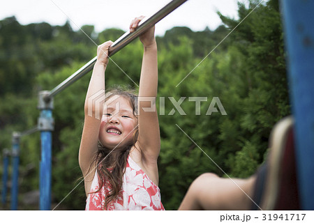 鉄棒で遊ぶ女の子の写真素材