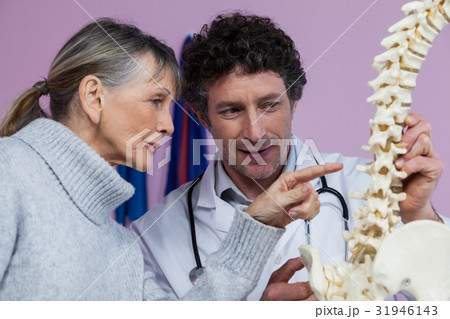 Physiotherapist explaining the spine model to patient 31946143