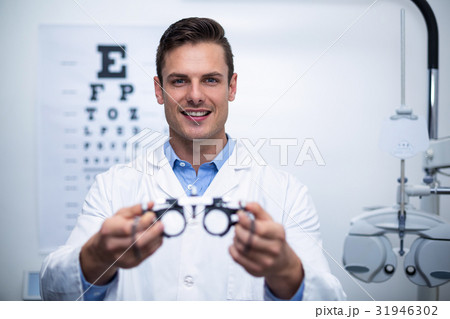 Smiling optometrist holding messbrille 31946302