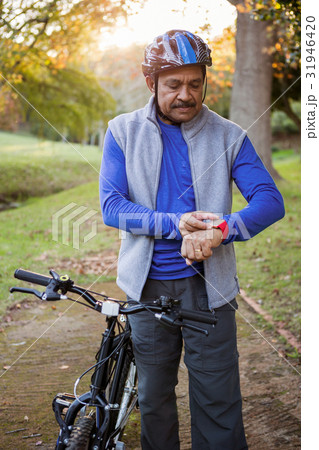 Man touching his watch next to his bike Man touching his watch next to his bike 31946420