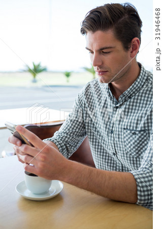 Man using his mobile phone in coffee shop 31946468