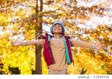 Happy boy with arms outstretched against autumn trees Happy boy with arms outstretched against autumn trees 31946526