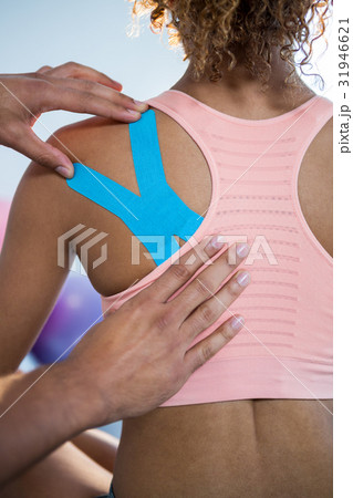 Physiotherapist sticking tape on female patient 31946621