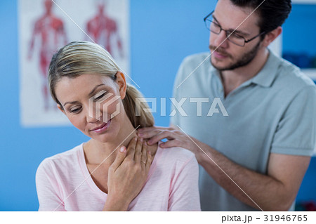 Physiotherapist stretching neck of a female patient Physiotherapist stretching neck of a female patient 31946765