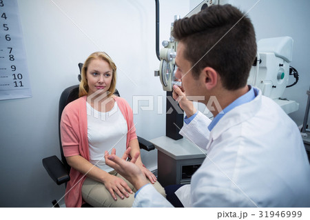 Optometrist assisting female patient 31946999