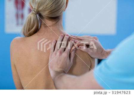 Male physiotherapist giving shoulder massage to female patient 31947623
