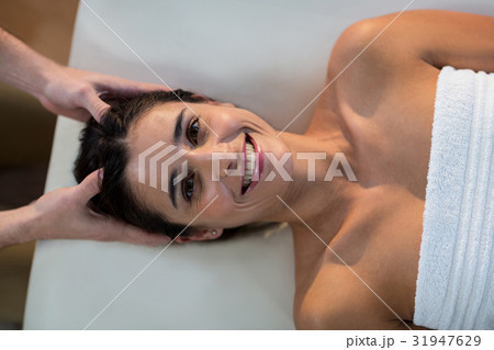 Male physiotherapist giving head massage to female patient 31947629