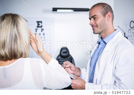 Male optometrist taking eye test of female patient 31947722