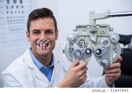 Smiling optometrist adjusting phoropter Smiling optometrist adjusting phoropter 31947941