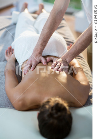 Male physiotherapist giving back massage to female patient 31948091