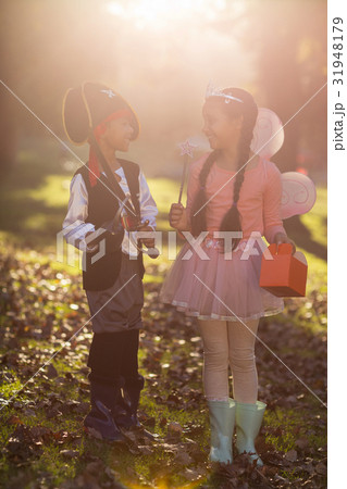 Happy siblings wearing costumes at park 31948179