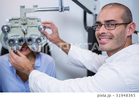 Smiling optometrist examining female patient on phoropter Smiling optometrist examining female patient on phoropter 31948365