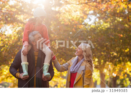 Father carrying daughter on shoulder while standing at park 31949385