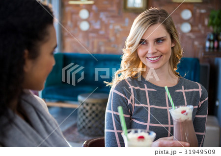 Female friends interacting with each other while having coffee Female friends interacting with each other while having coffee 31949509