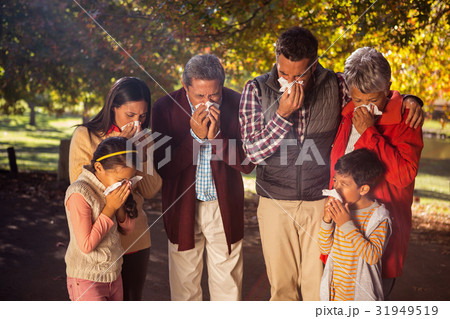 Family blowing nose while in park 31949519