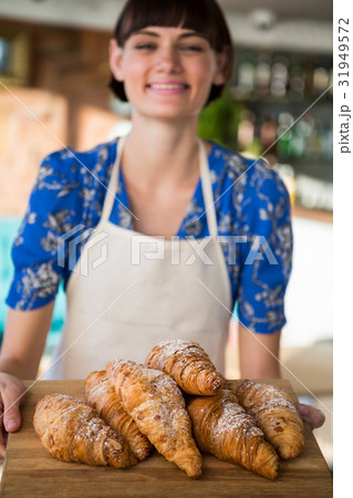 Smiling waitress holding a tray of croissants Smiling waitress holding a tray of croissants 31949572