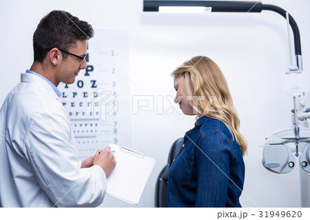 Optometrist discussing eye test report with female patient Optometrist discussing eye test report with female patient 31949620
