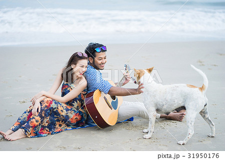 A picture of a couple sitting, playing with the dog and smiling A picture of a couple sitting, playing with the dog and smiling 31950176