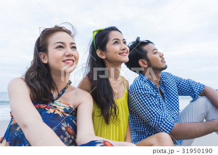 A picture of a man and two women sitting and looking something 31950190