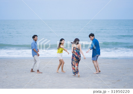 four people are smiling and playing on the seashore 31950220