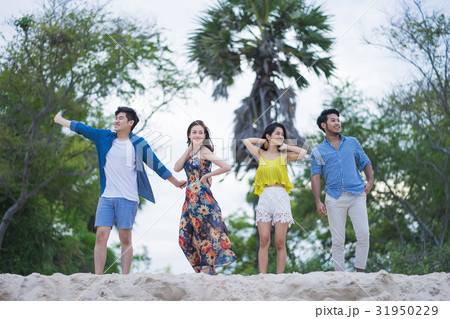 A group of four people is standing on the sand with pleasure A group of four people is standing on the sand with pleasure 31950229