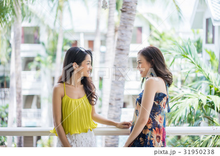 Two young girls are standing at the balcony and chatting happily 31950238