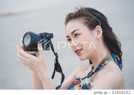 A beautiful girl is holding a camera and taking photo 31950252