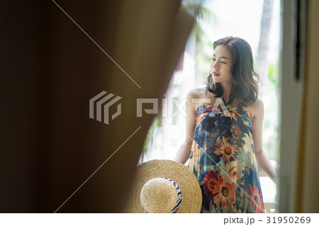 A nice woman is holding hat and standing in a balcony A nice woman is holding hat and standing in a balcony 31950269