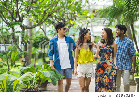 two young couples with arm in arm are walking and smiling in garden 31950287