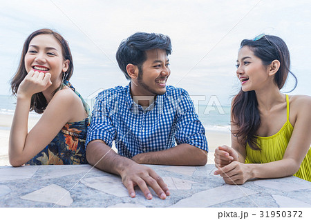 A man and two girl are talking happily near the beach 31950372