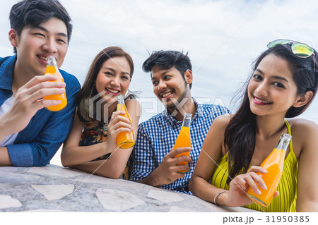 two men and two women are sitting and drinking juice happily 31950385